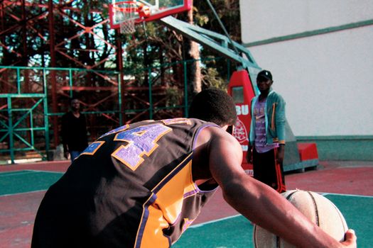 An energetic outdoor basketball game with players in action on a court during the day.