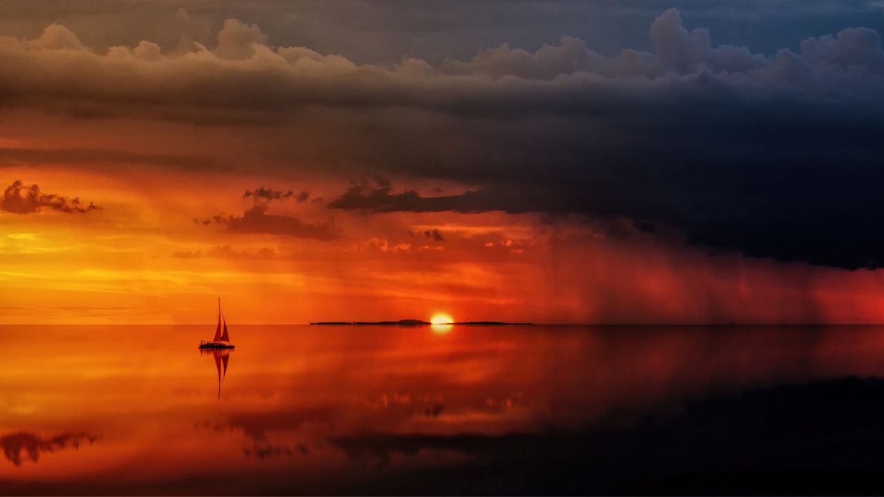 a tranquil seascape with a sailing boat at sunset reflecting on calm w