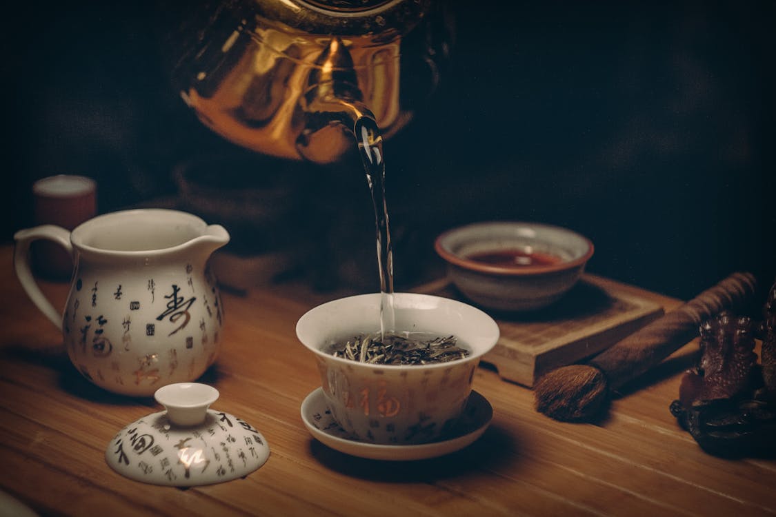 Traditional Chinese tea set with tea being poured into a cup.