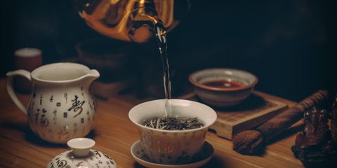 Artistic depiction of a traditional Chinese tea ceremony with porcelain teaware and hot water pour.