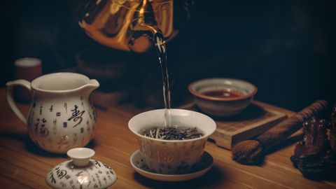 Artistic depiction of a traditional Chinese tea ceremony with porcelain teaware and hot water pour.