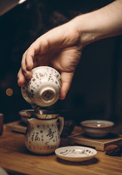 在舒适的室内茶道中，一只手熟练地将茶倒入传统的中式茶杯