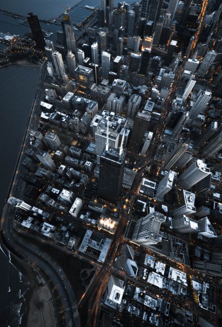 Dramatic aerial view of Chicago's illuminated skyline at twilight, showcasing iconic skyscrapers along the river.