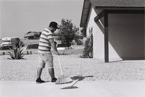 Photo En Niveaux De Gris D'un Homme Balayant L'allée