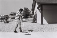 Grayscale Photo of Man Sweeping Driveway