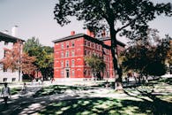 一座历史悠久的红砖大学建筑，四周绿树成荫，步行道环绕