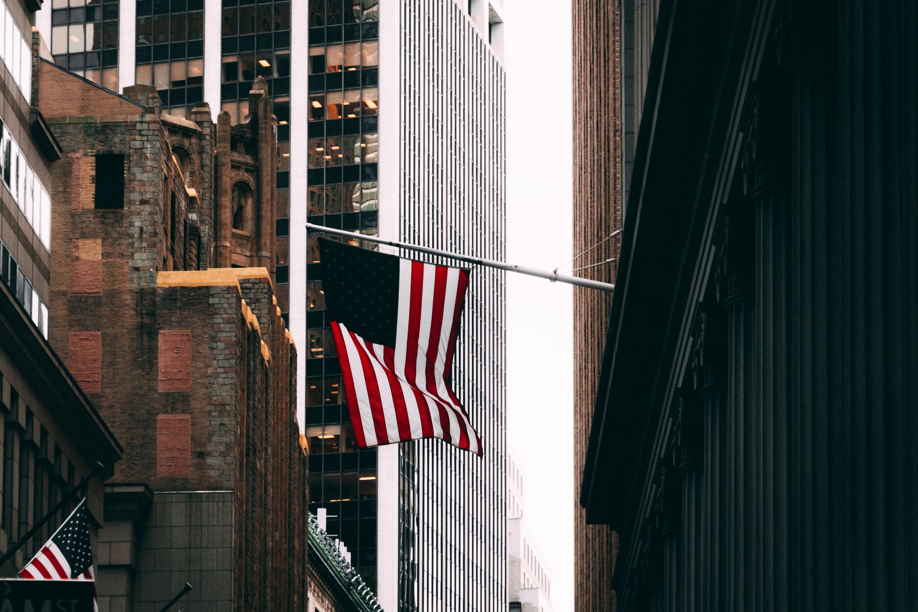 Skyscrapers and American flag in a bustling city financial district street scene.