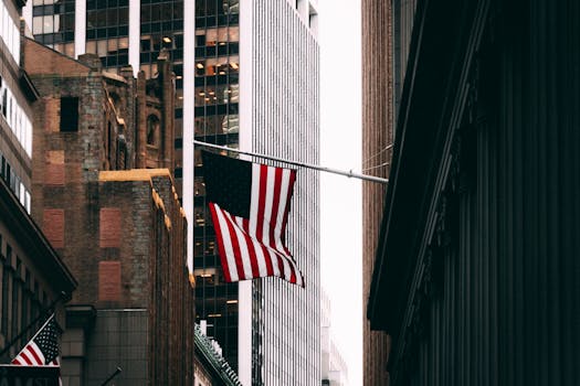 Skyscrapers and American flag in a bustling city financial district street scene.