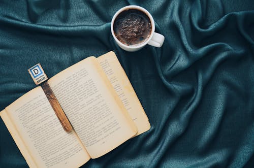 Tasse En Céramique Blanche Remplie De Boisson Brun Foncé à Côté Du Livre Ouvert