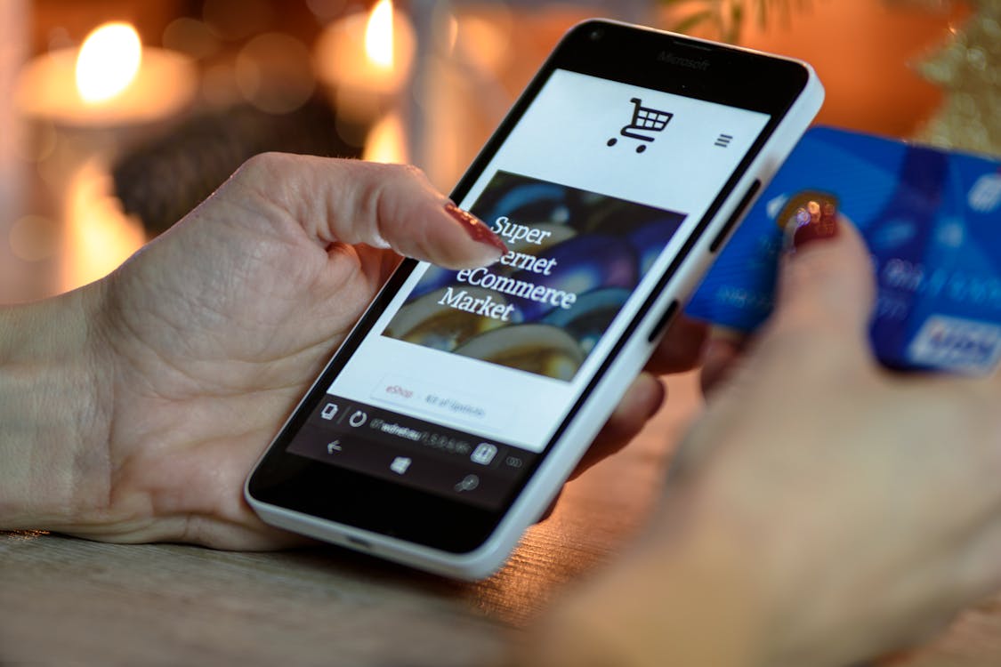 Person Using Black And White Smartphone and Holding Blue Card