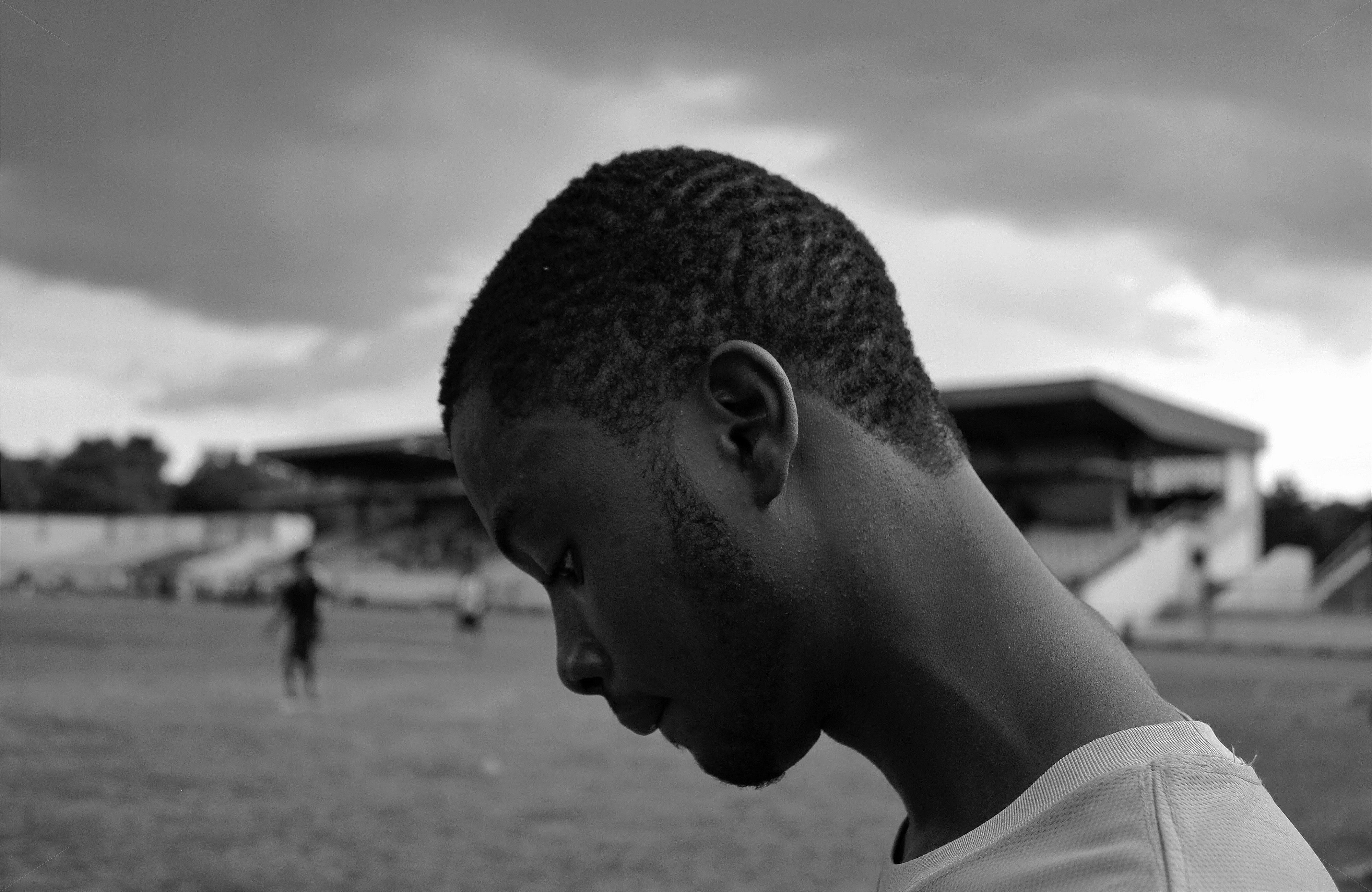 A powerful, close-up photo of an athlete in a moment of quiet contemplation, headphones on, away from the field of play