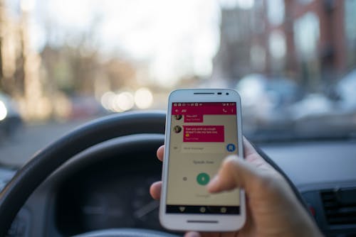 Free Person Holding White Smartphone Inside Vehicle Stock Photo