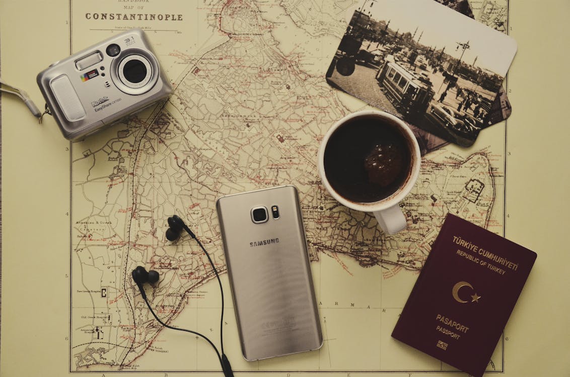 Free Silver Camera Near Black Coffee in Mug, Silver Samsung Galaxy S7, Turkey Passport, and Black Earbuds Stock Photo