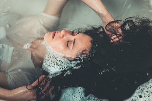 Free Woman Lying in Bathtub Filled With Water Stock Photo
