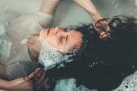 一个女人的宁静特写，她在装满肥皂水的浴缸里放松