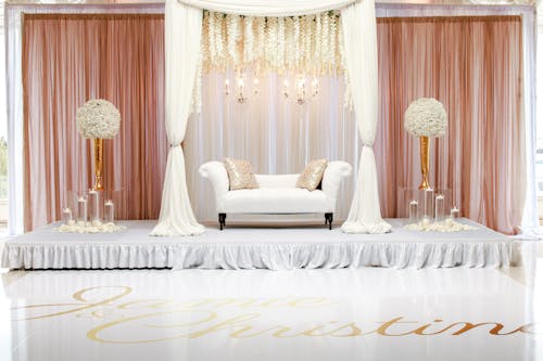 White Fabric Loveseat With Two Flower Centerpieces on the Side