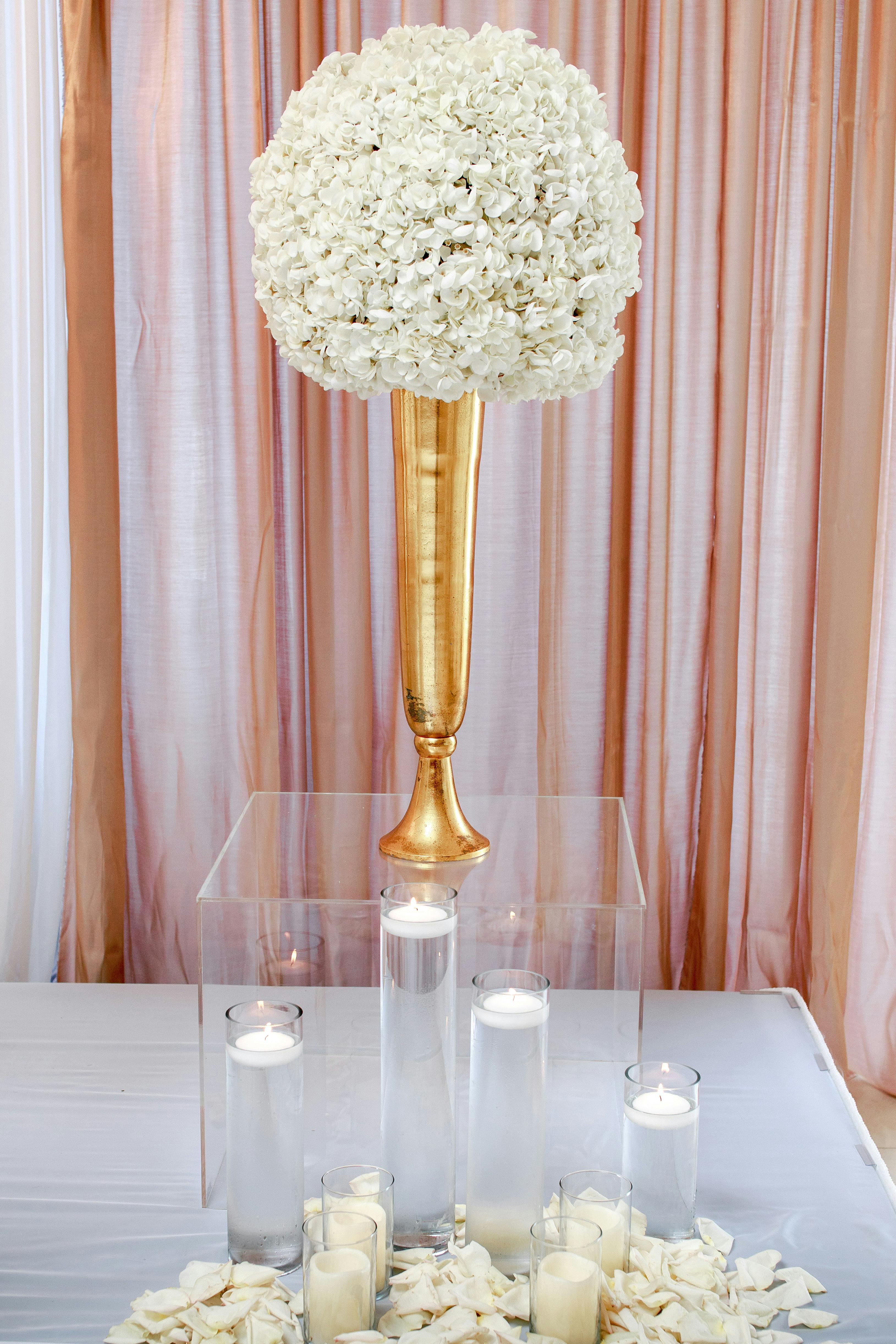 white flower centerpiece on clear glass box with candles