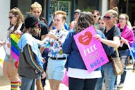 在充满活力的骄傲游行现场，参与者们举着标语微笑，庆祝平等