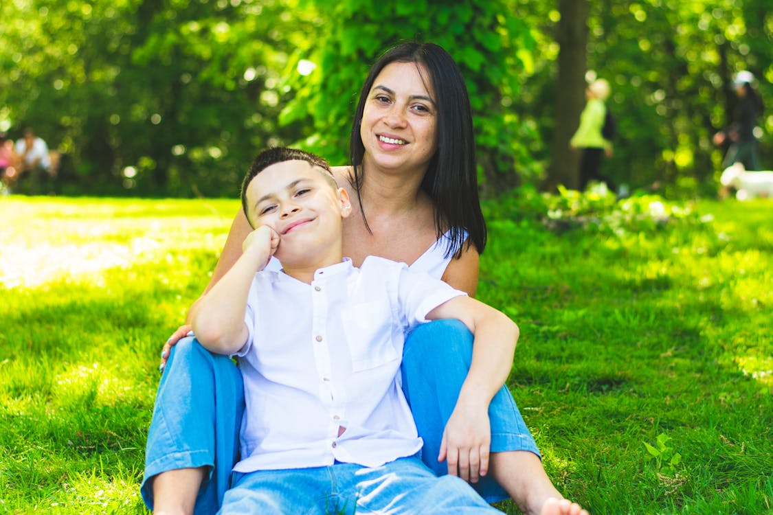 Mother and son sitting on Green Grass Field