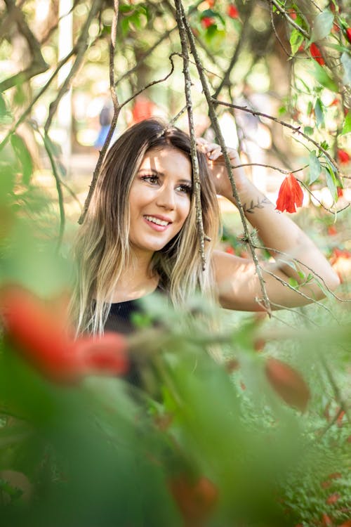 Smiling Woman Standing Under Red Flowered Tree