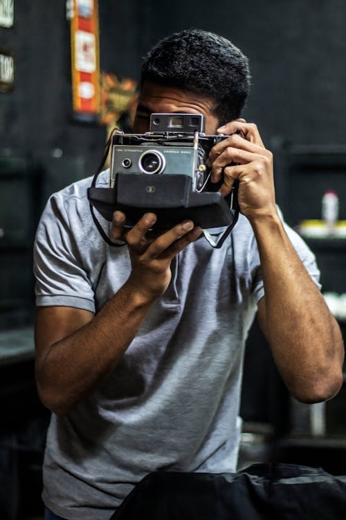 Man Holding Gray and Black Camera Inside Well Lit Room