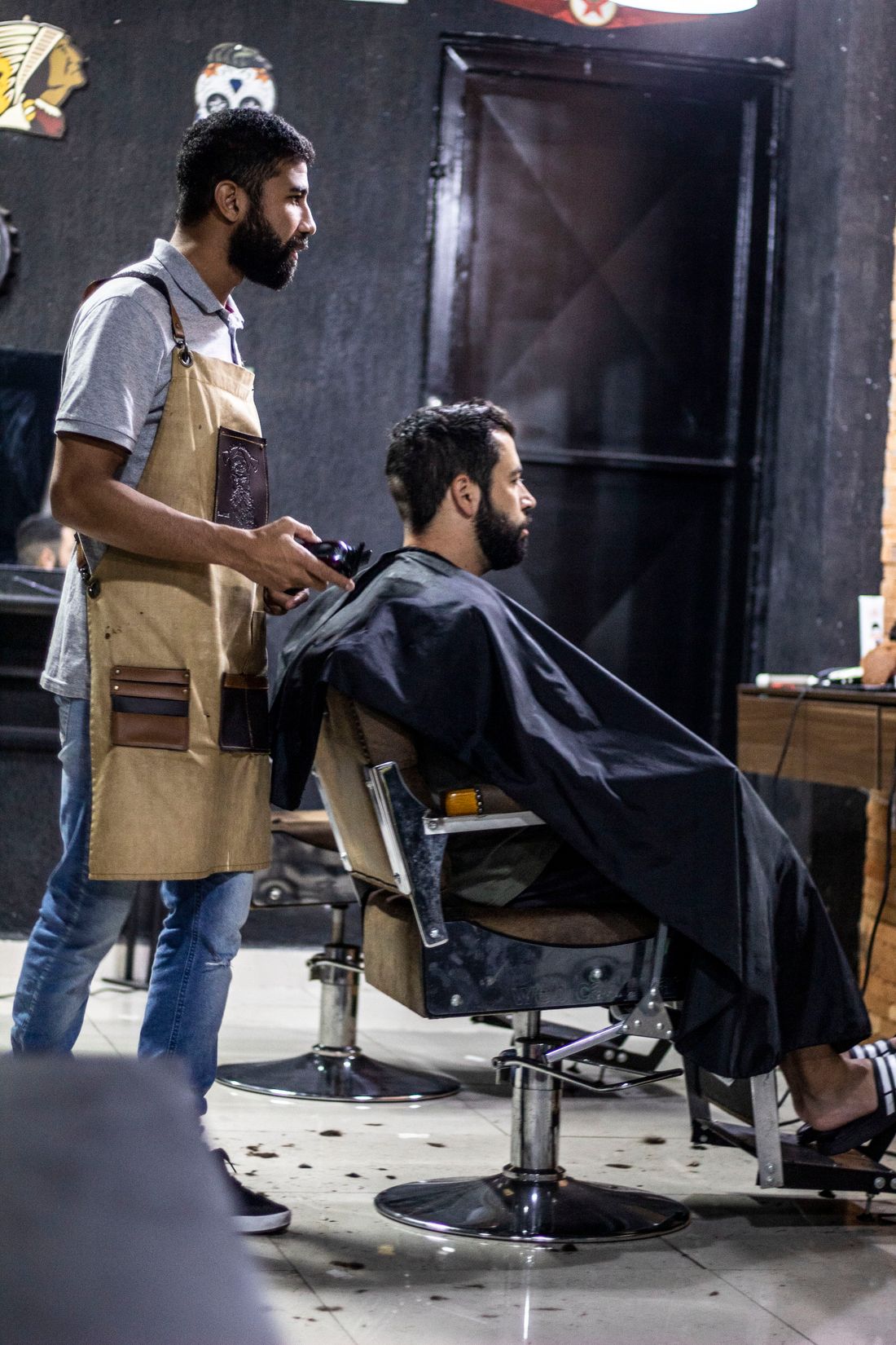 Barber in a work apron giving a client a clipper cut