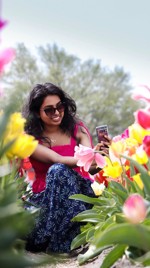A woman in sunglasses sitting in a field of flowers
