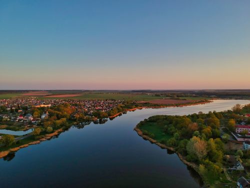 Free Stunning aerial view of a scenic riverside village with lush greenery at sunset in Niaśviž, Belarus. Stock Photo