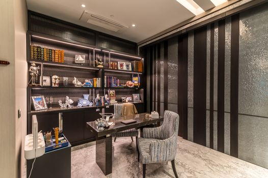 Stylish office interior featuring a desk, chair, bookshelf, and decorative items under soft lighting.
