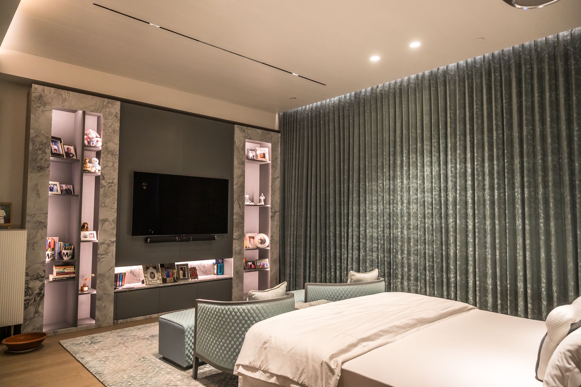 A Bedroom With TV Set And Photographies on Shelves
