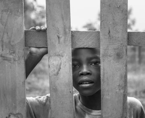 Gri Tonlamalı Ahşap çit Arkasında Duran çocuk Fotoğrafı