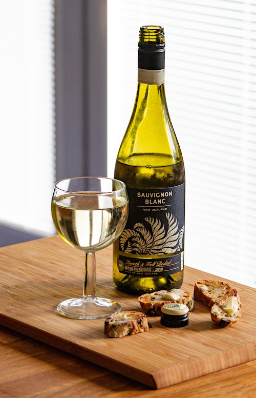 Bottle of Sauvignon Blanc and Glass With Slices of Cheese