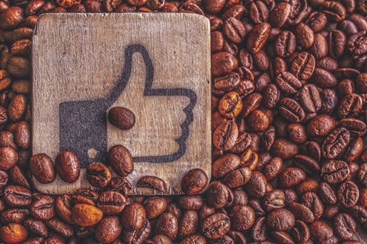 一堆烤咖啡豆上放着一个木制竖起大拇指的符号，代表欣赏