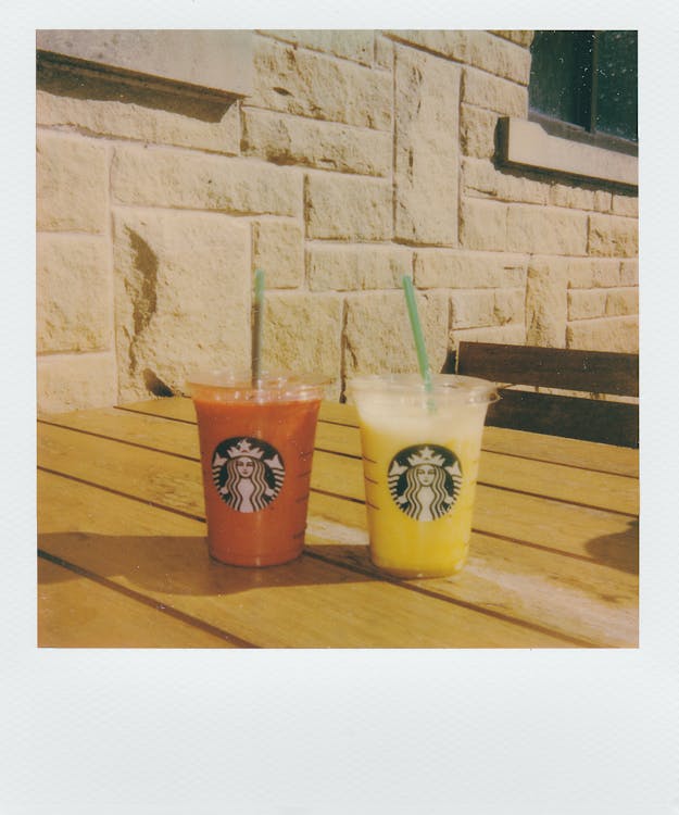 Two Orange and Yellow Starbucks Juices in Plastic Cups With Lids and Straws