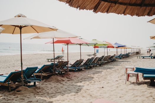 Colorful beach umbrellas and lounge chairs at Hội An beach, Vietnam, perfect for relaxation.