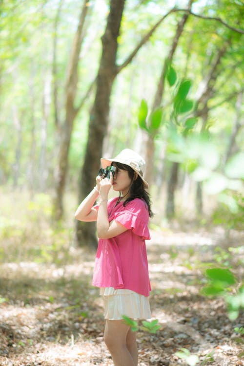 A girl in pink shirt and hat looking through binoculars