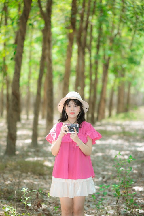 A woman in a pink shirt and hat is taking a picture