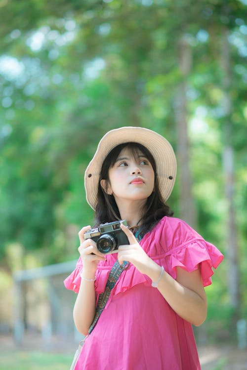 A young woman in a pink dress holding a camera