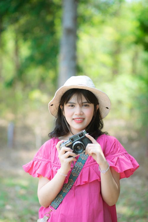 A woman in a pink dress holding a camera