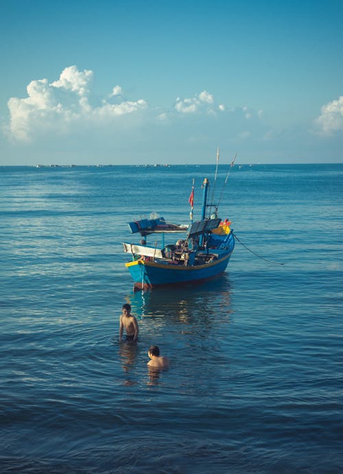 A boat in the ocean with two people in the water