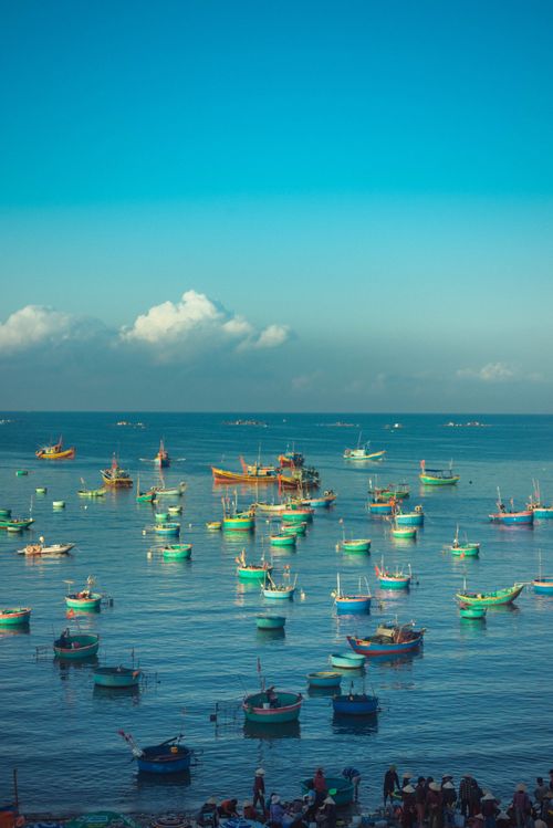 Free A scenic view of colorful fishing boats floating on a calm blue sea under a clear sky. Stock Photo