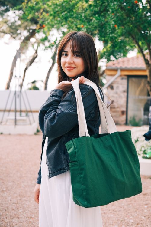 Free Woman in denim jacket poses with green bag outdoors in Adalar, Turkey. Stock Photo