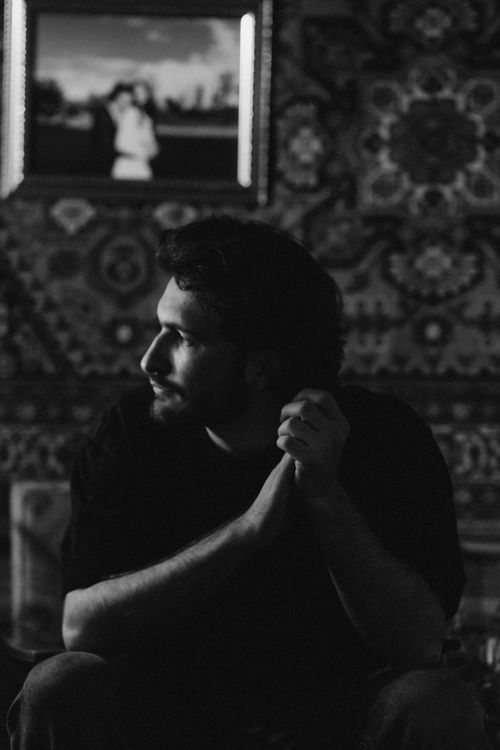 Free Black and white portrait of a man with facial hair sitting indoors, looking contemplatively. Stock Photo