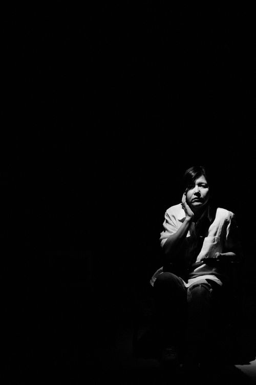 Free Artistic black and white portrait of a woman sitting in dramatic lighting. Stock Photo