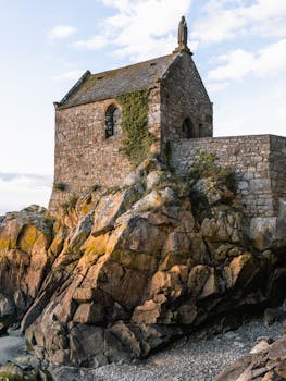 在阳光明媚的日子里，圣米歇尔山岩石悬崖上的石教堂，凸显了古老的建筑和令人惊叹的风景