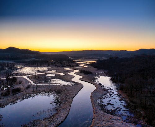 A river flows through a valley at sunset