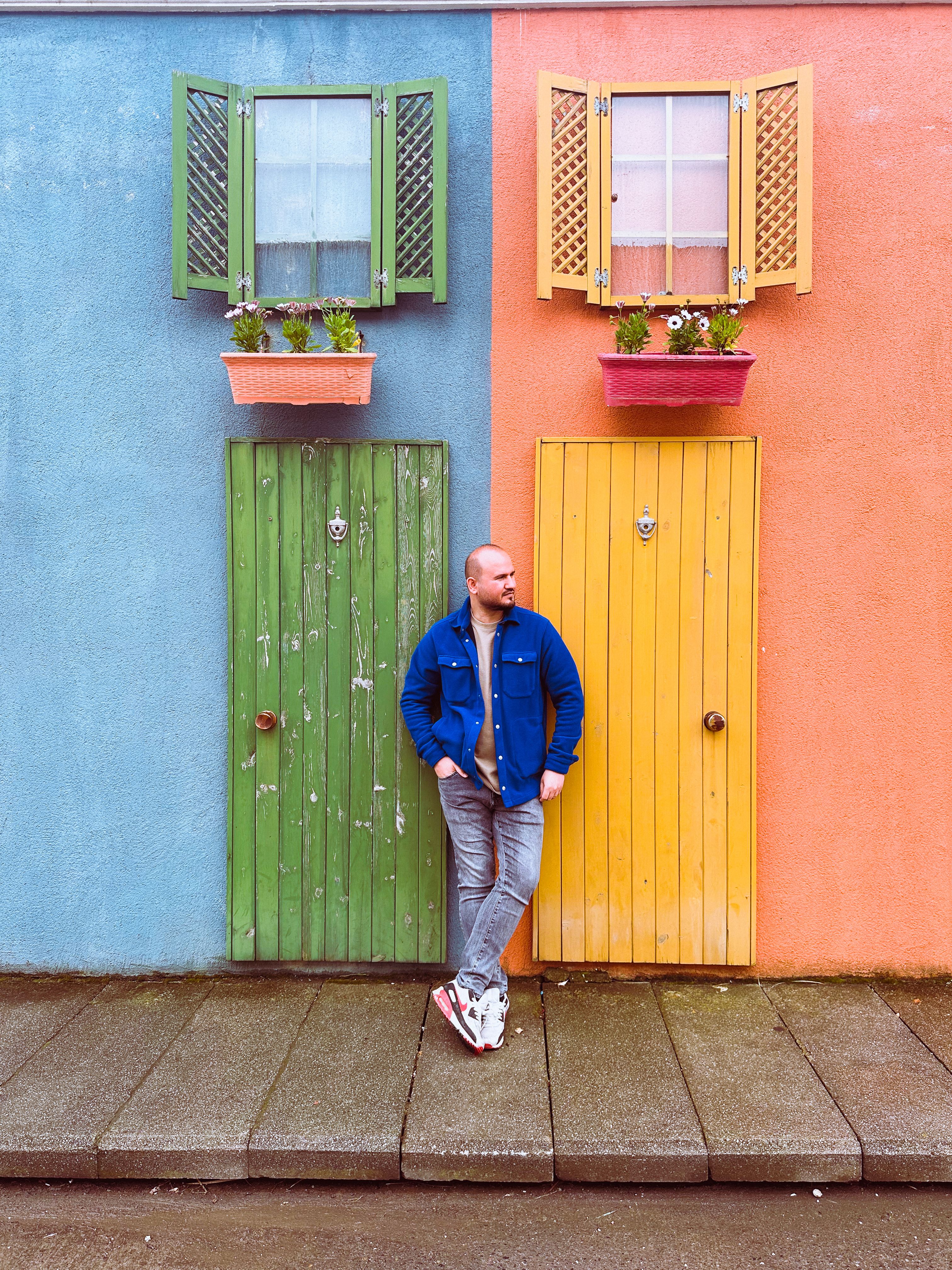 Man in a vibrant street scene with colorful doors and plants in İstanbul, Türkiye.
