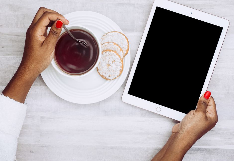 Top view of a person with coffee and a tablet, evoking a modern lifestyle.