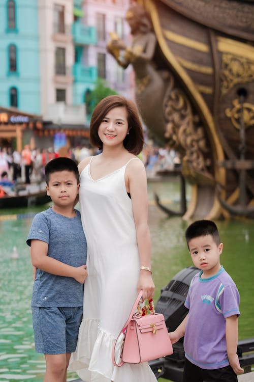 A woman and two children pose for a photo in front of a boat