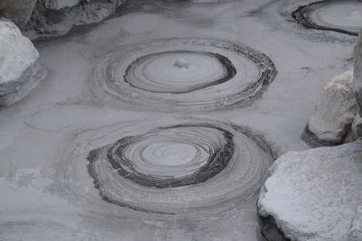 Gray geothermal mud pools with bubbling patterns in Beppu, Japan.